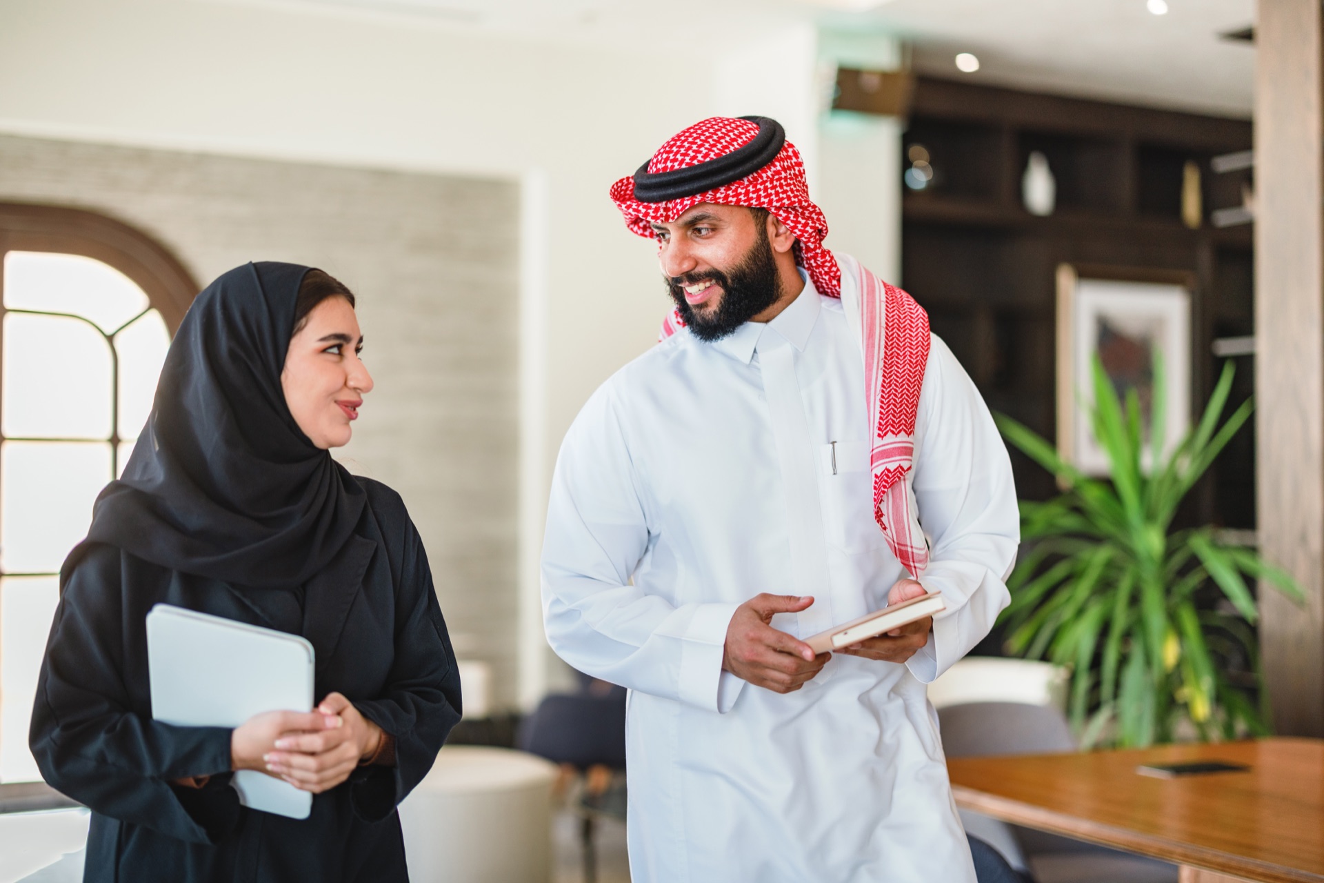 Saudi finance professionals reviewing strategy on a tablet