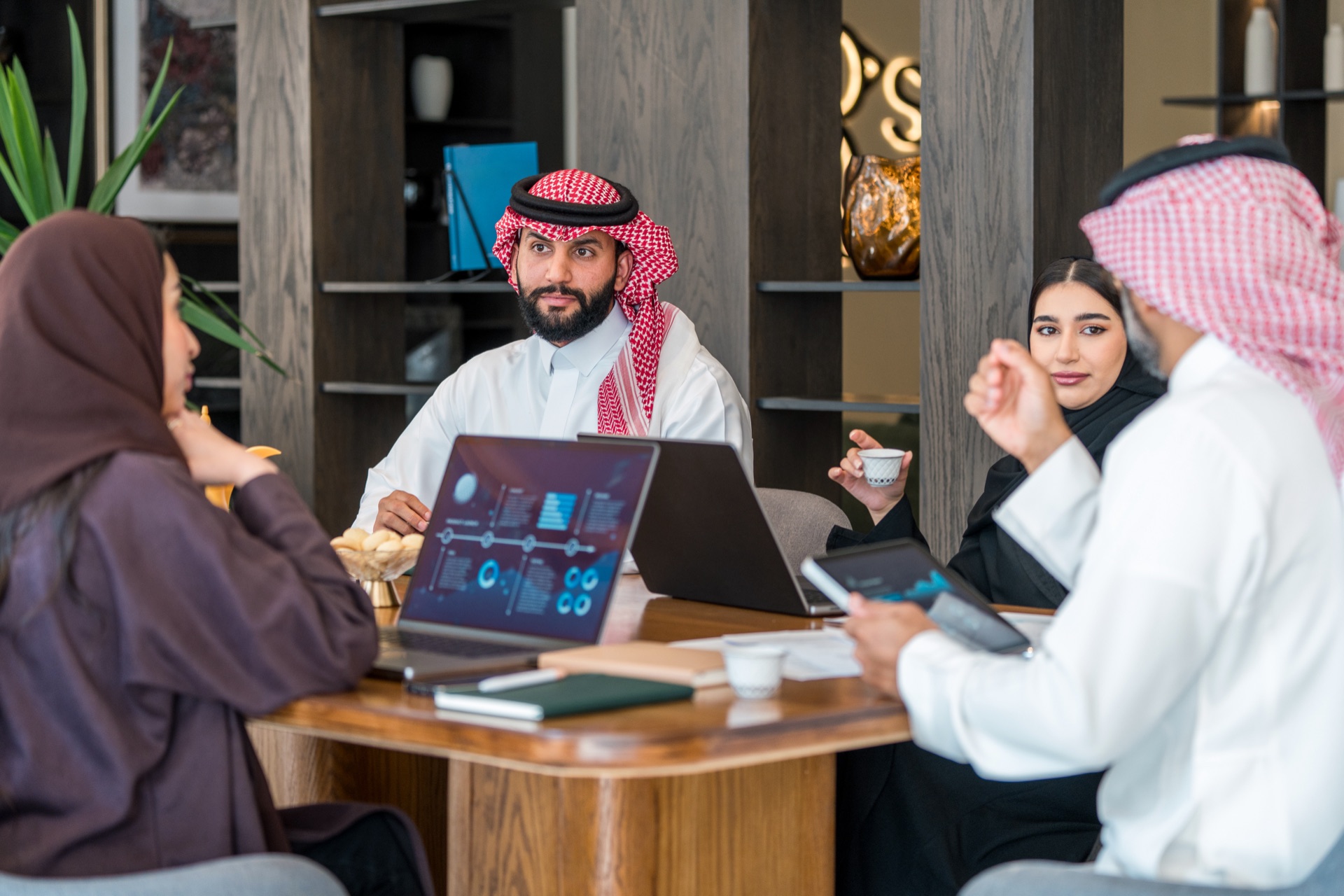Saudi professionals collaborating with data dashboards in a modern Riyadh office